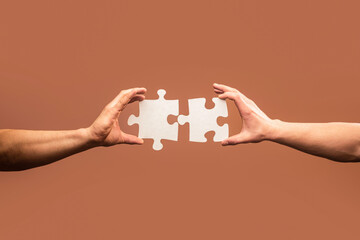 Wall Mural - Holding puzzle. Business solutions, success and strategy concept. Two hands trying to connect couple puzzle piece on gray background. Teamwork concept. Closeup hand of connecting jigsaw puzzle