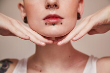 Woman With Piercing At Her Face And Ear Tunnels Posing With Hands Near Her Face