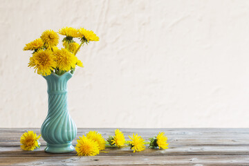 Wall Mural - yellow dandelions in blue vase on white background