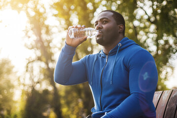 Poster - Man resting on bench after exercise and  drinking water .