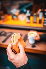 Close up alfajor cookie hot cappuccino white coffee cup with heart shape latte art whit hand of a man