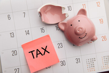 Broken piggy bank on a white calendar background, tax time concept