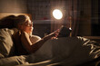 © alfa27 - Beautiful female in pajamas and eyeglasses lying on bed reading book, alone at night. Caucasian short haired lady in bedroom, charming cute woman in room lighted by lamp