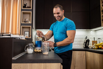 Young muscular man preparing ingredients for a tasty shake in the kitchen