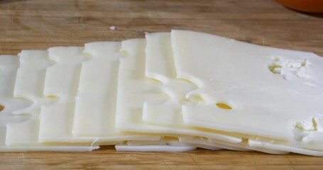 Wall Mural - Slices of organic Swiss cheese on a cutting board slider shot