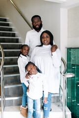 Wall Mural - Happy black family posing for photograph on staircase