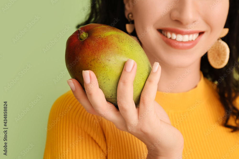 Beautiful woman with fresh mango on color background