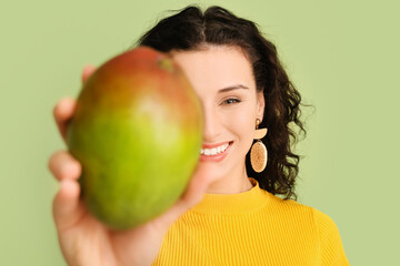 Wall Mural - Beautiful woman with fresh mango on color background