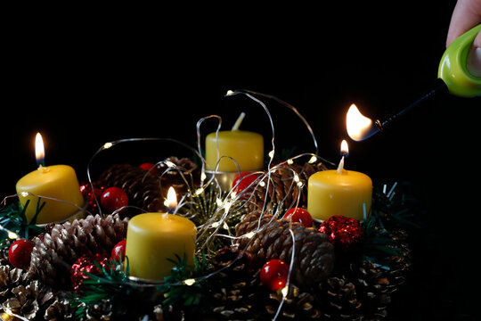 Advent wreath or crown.  Woman lignting yellow candles. Christmas composition.  France.