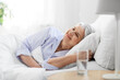 old age and people concept - happy smiling senior woman lying in bed at home bedroom