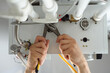 A man with tools checks the pipes that fit the gas heating boiler.