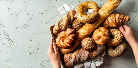 Breadstuff - bread rolls, baguette, bagel, burger bun and croissant on grey background