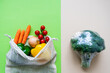 Gegensatz von Gemüse in einem Einkaufsnetz und Brokkolie in Plastik verpackt. Grüner und beiger Hintergrund. Isoliert.