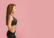 © Daria Lukoiko - Fitness girl smiling in black sportswear on a pink background. Slim woman with a beautiful athletic body and tanned skin