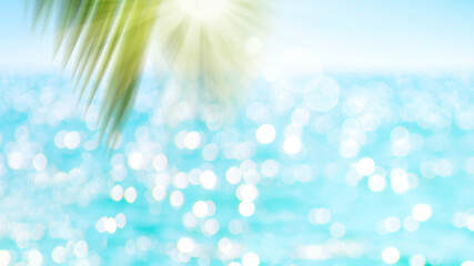 Wall Mural - Green blur palm leaf on ocean with bokeh sun light background.