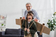 © LIGHTFIELD STUDIOS - Excited boy in aviator costume playing near blurred granddad
