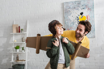 Wall Mural - Smiling boy in aviator costume standing near happy father