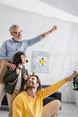 Wall Mural - Positive parents gesturing near boy in aviator helmet and wings