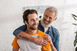 © LIGHTFIELD STUDIOS - Mature dad hugging cheerful son in living room