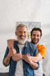© LIGHTFIELD STUDIOS - Smiling father and son looking at camera while embracing at home