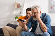 © LIGHTFIELD STUDIOS - Worried man and blurred son watching tv at home