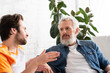 © LIGHTFIELD STUDIOS - Blurred man talking with mature father on couch