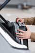 © LIGHTFIELD STUDIOS - cropped view of man putting suitcase in car trunk