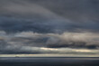 Ujęcie szarego zachmurzonego nieba nad morzem oraz samotnego statku pod nimi