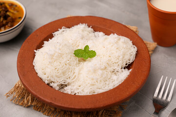 Noolappam , idiyappam rice noodles string hopper popular steam cooked Kerala breakfast hot spicy chickpea curry sweet coconut milk in clay plate Tamil Nadu India South Indian noolputtu Sri lankan food