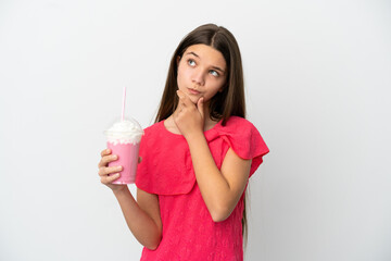 Wall Mural - Little girl with strawberry milkshake over isolated white background having doubts