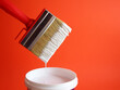 Brush with white paint. White paint dripping from a brush into a jar isolated on a red background. creativity concept.