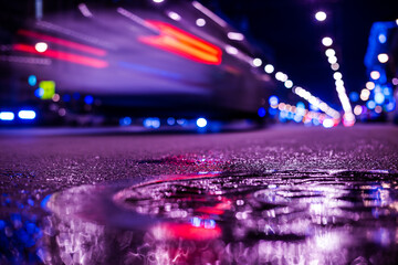 Nights lights of the big city, the main city street with a racing car. Close up view from the level of the dividing line