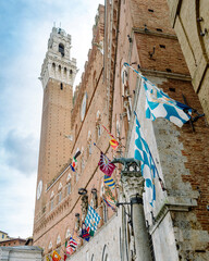 Wall Mural - Siena, Italy - The flags of the districts displayed on the facade of the public building