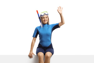 Poster - Woman in a wetsuit and a diving mask sitting on a banner and waving