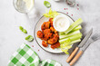 Buffalo style barbecue cauliflower  with fresh celery sticks  and sauce . Light gray stone background. Top view