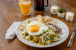 © Gener Vázquez - Mexican traditional chilaquiles breakfast Green red salsa Orange juice wooden