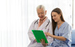 © Bangkok Click Studio - A senior older female doctor visits the patient's room and explains information on the chart for the patient