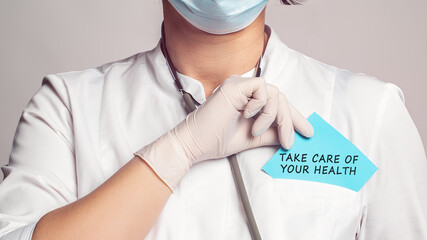 Wall Mural - Cropped view of doctor in a white coat and sterile gloves holding a note with text - take care of your health