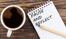PAUSE AND REFLECT Text On Notebook With Coffee On Wooden Background