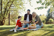 © gstockstudio - Happy young mother and father with little boy smiling while having picnic outdoors