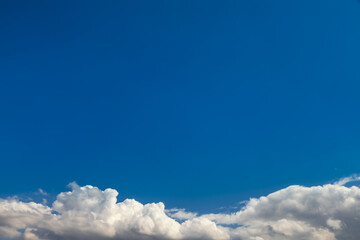 blue sky with white fluffy clouds at the bottom