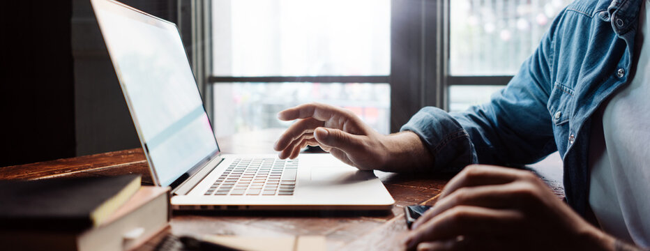 Close-up of male hands with laptop. Man is working remotely at home. Freelancer at work