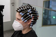 young woman, girl is getting perm,  hair curlers on head at hairdressers salon, wearing mask because of corona virus