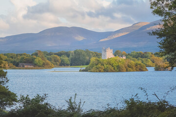 Wall Mural - Golden hour sunset light on scenic mountain landscape of the historic medieval Ross Castle on Lough Leane lake in Killarney National Park, County Kerry, Ireland.