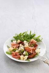 Wall Mural - Salad arugula, Parma ham with sun-dried tomatoes, mozzarella slices, croutons, capers, seasoned oil and spices