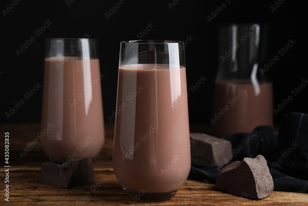 Delicious chocolate milk in glasses on wooden table - obrazy, fototapety, plakaty 