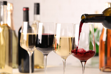 Pouring red wine from bottle into glass, closeup