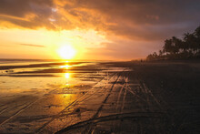Empty Black Sand Beach With Bike Trails During Beautiful Orange Sunset