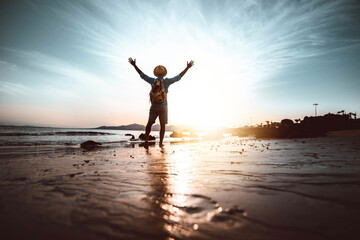 Wall Mural - Man with arms up on the beach at sunset - Happiness and wellbeing concept