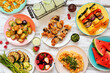 © Jenifoto - Vegan summer bbq or picnic table scene. Overhead view on a white wood background. Fruit, grilled vegetables, skewers, cauliflower steak and lemonade. Meat substitute concept.
